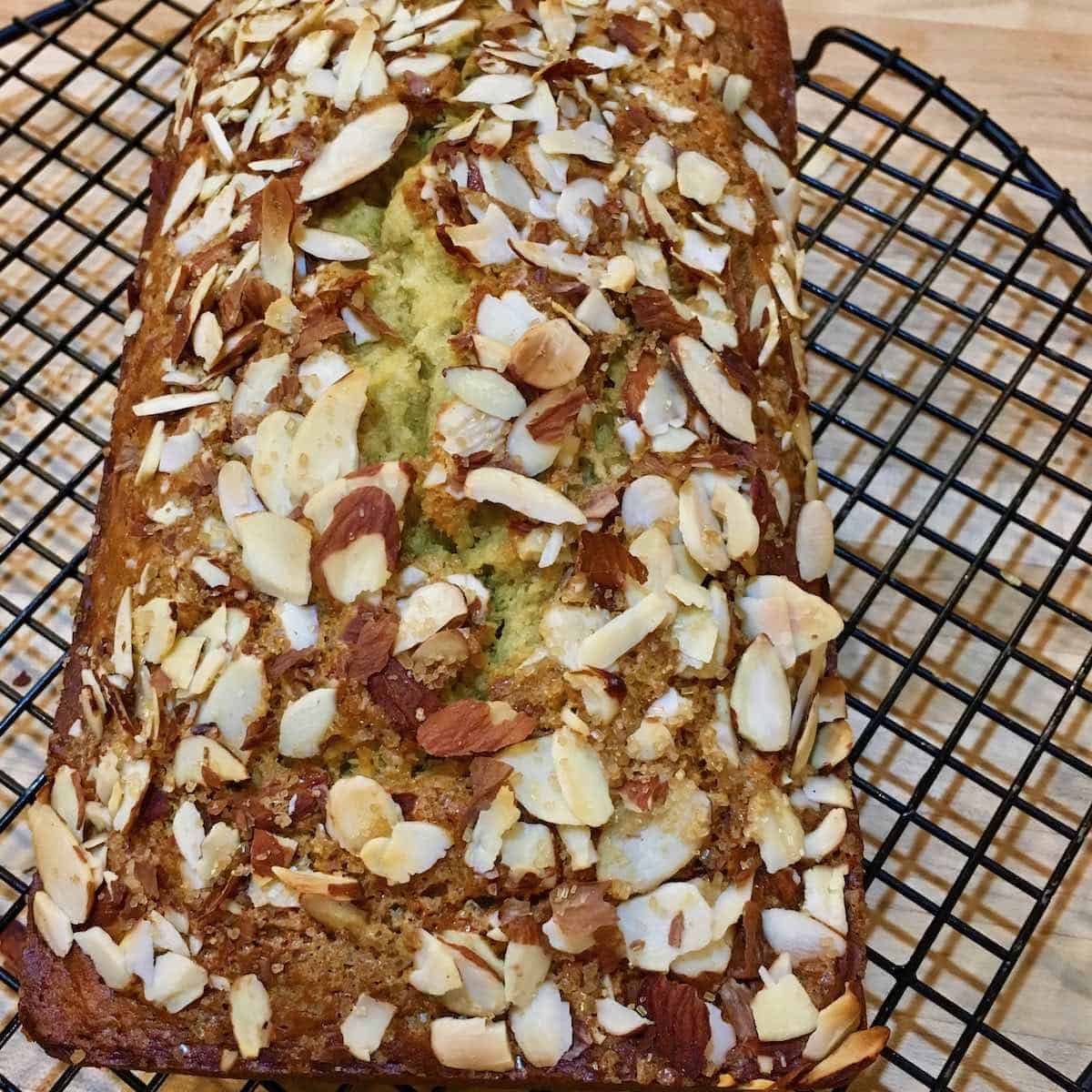 Banana bread topped with almonds on cooling rack.