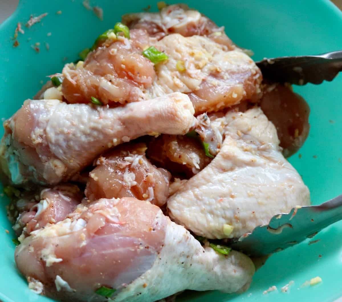Marinating raw chicken pieces for a flavorful spring chicken stew.