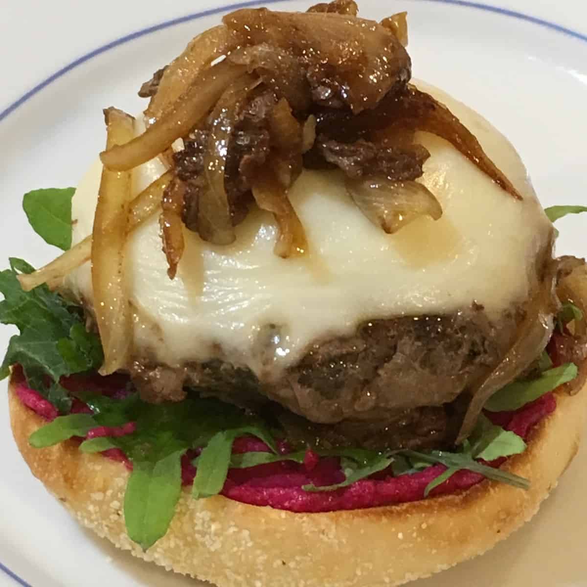 Plated mushroom blend burger topped with cheese and onions.