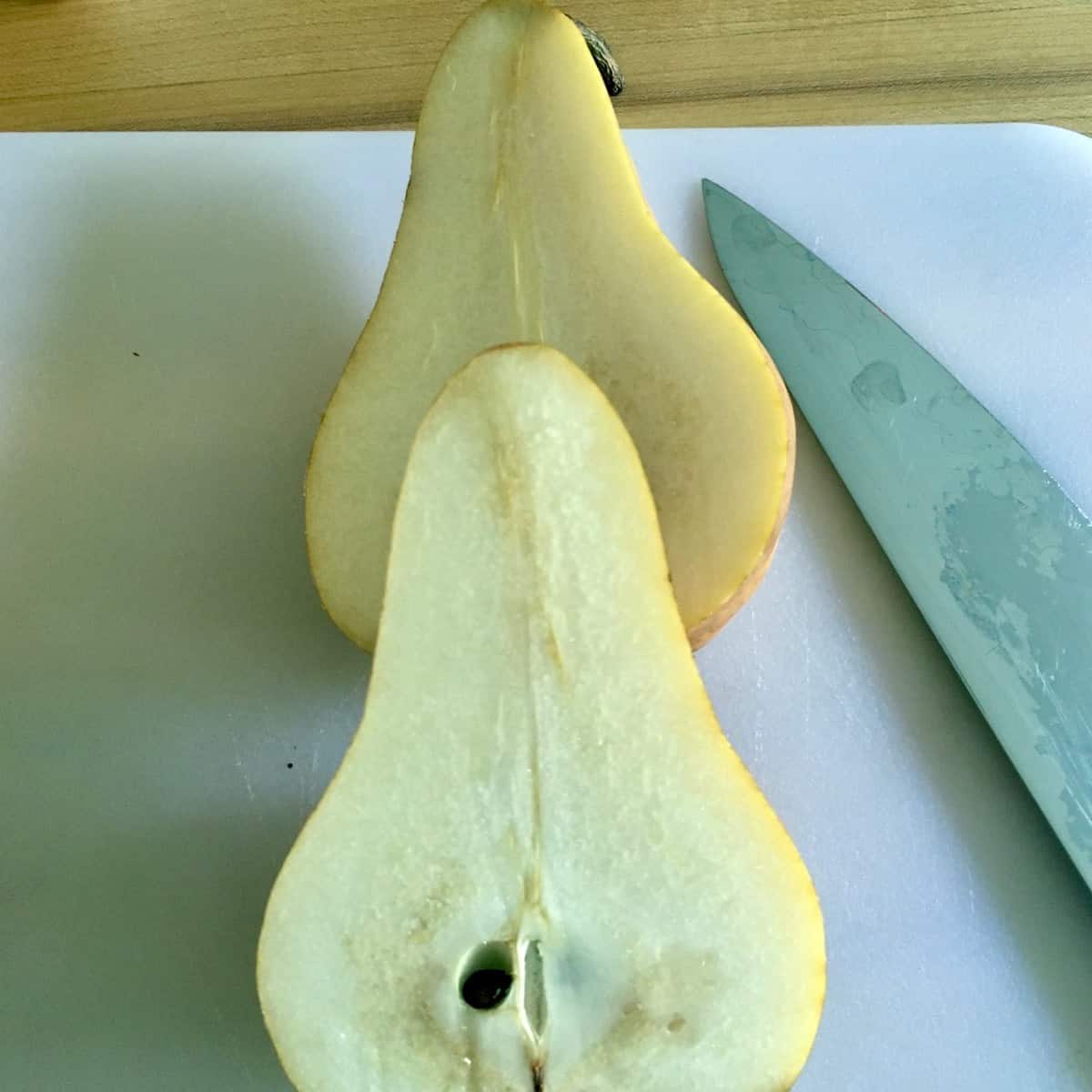 Sliced pear with knife on cutting board prepping for salted chocolate pear pound cake.