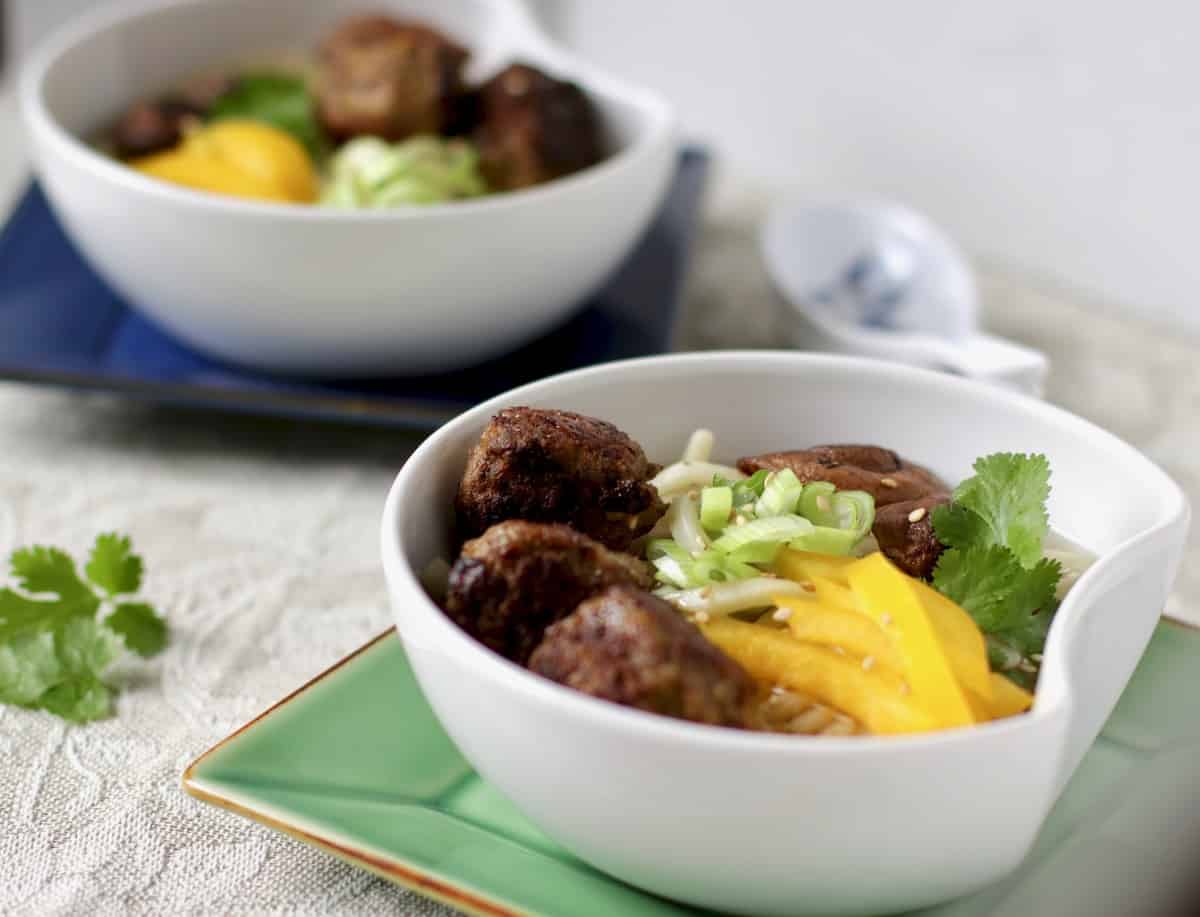 Two bowls of mushroom meatball noodle soup.