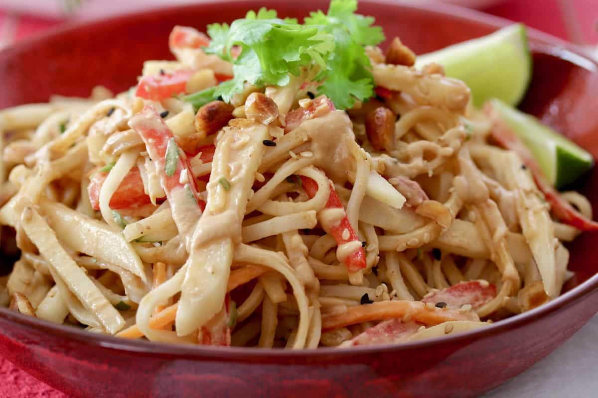 pear pad Thai salad served in red bowl garnished with lime and cilantro