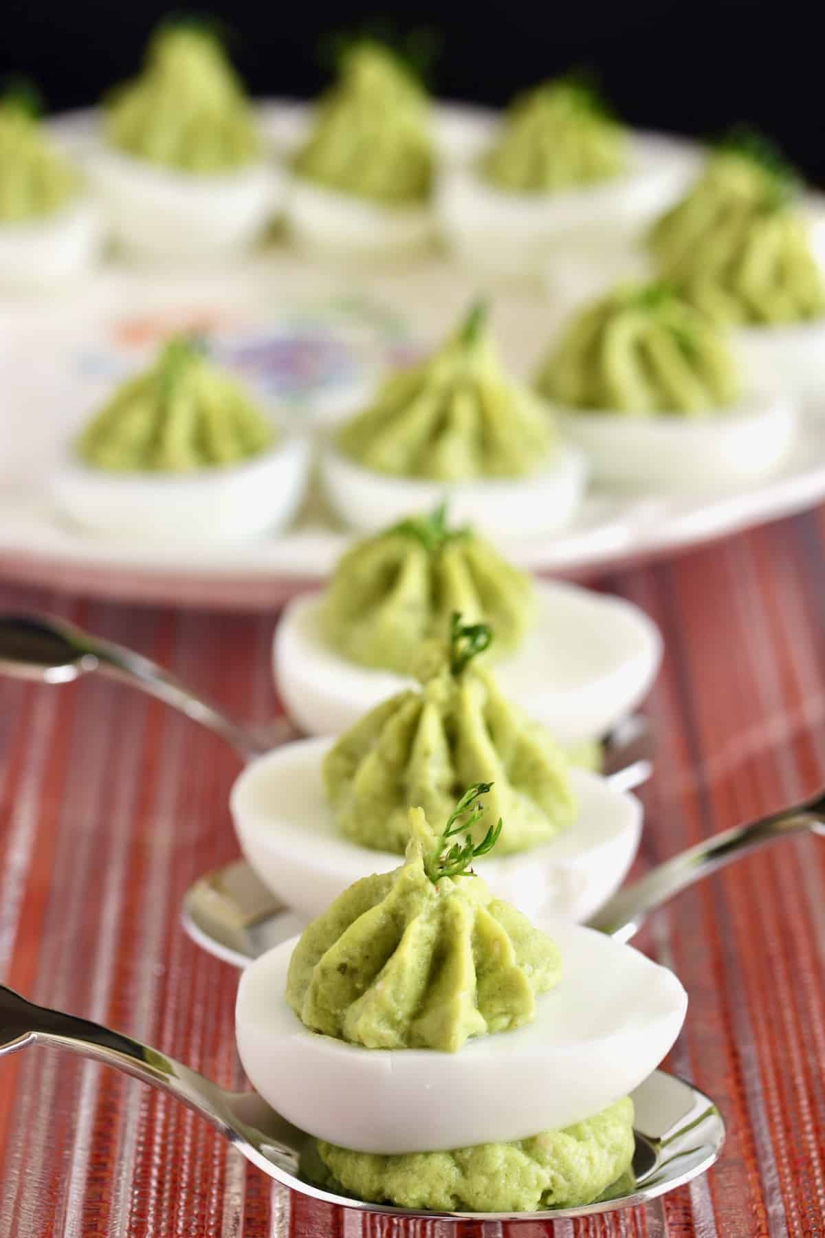 salsa verde deviled eggs on spoons are among the best summer appetizers